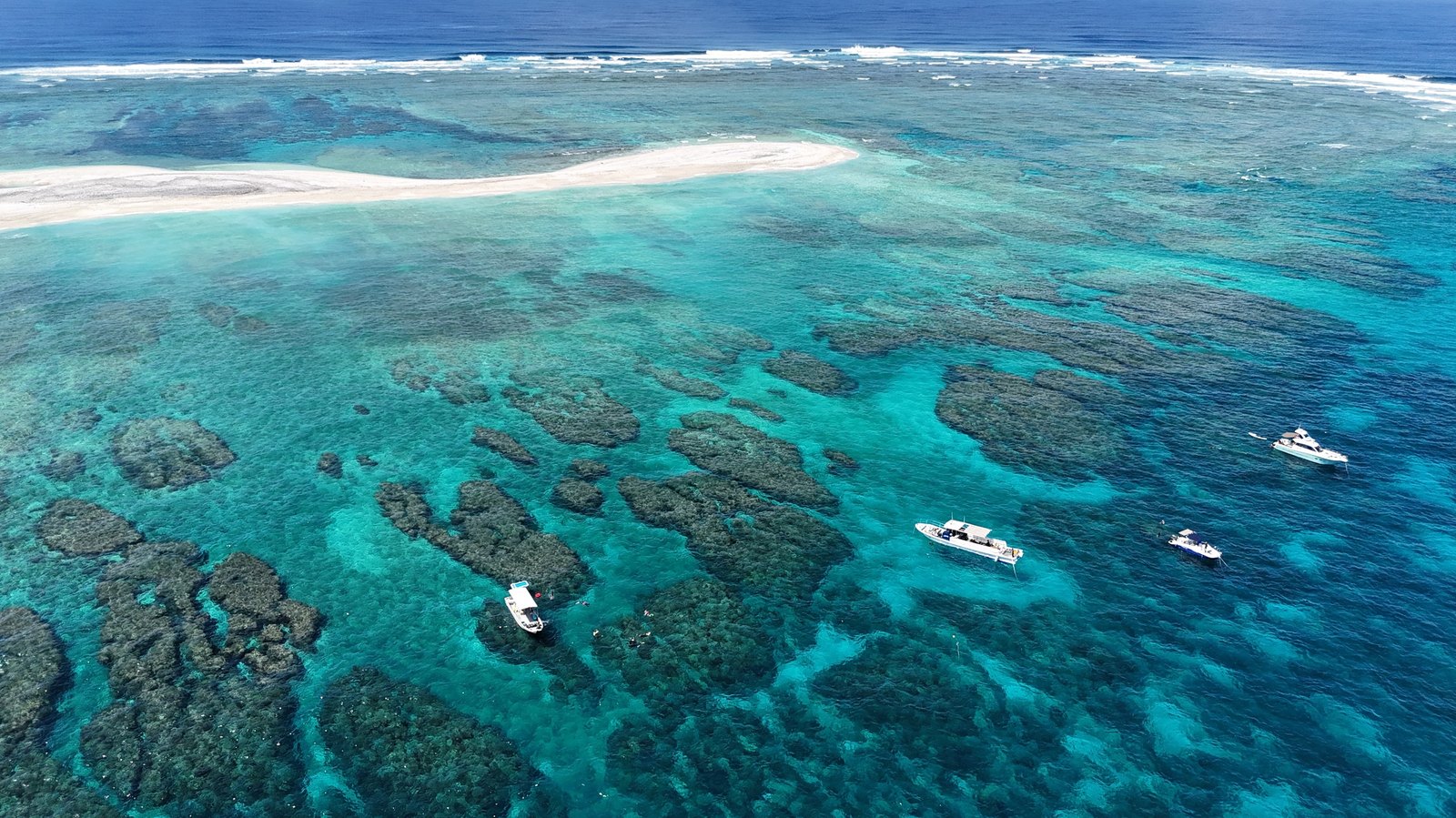 Aerial view of Chibishi, Okinawa — white sandbar, coral reef and three widely spaced boats on clear water